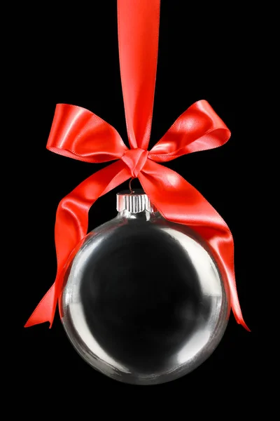 Σαφές χριστουγεννιάτικο στολίδι που κρέμεται από γυαλιστερή κόκκινη κορδέλα και τόξο. — Φωτογραφία Αρχείου