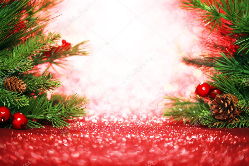 Christmas tree branches on glittering red background