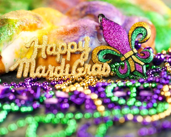 Happy Mardi Gras text in gold glitter and a king cake with yello — Stock Photo, Image