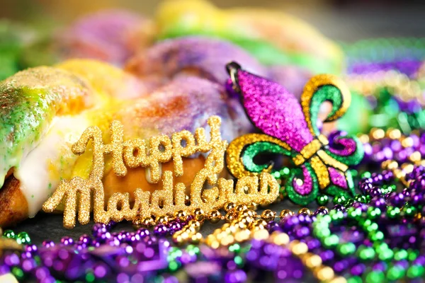 Happy Mardi Gras text in gold glitter and a king cake with yello — Stock Photo, Image