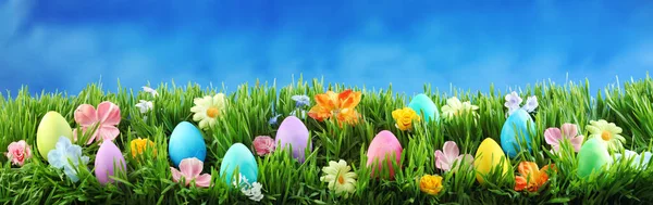 Yeşil Çimlerin Üzerinde Parlak Renkli Paskalya Yumurtaları Mavi Gökyüzüne Karşı — Stok fotoğraf