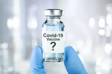 Coronavirus, Covid 19 virüsü ve aşı tüpü içeren mavi eldivenli olası tedavi konsepti.