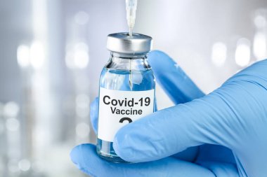 Coronavirus, Covid 19 virüsü ve aşı tüpü içeren mavi eldivenli olası tedavi konsepti.