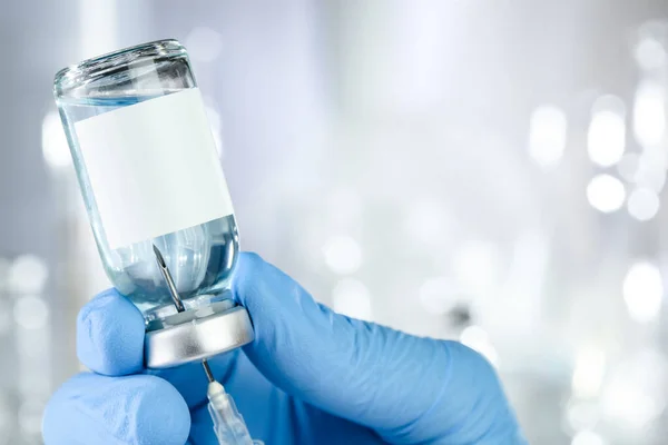 青い液体と黒の白いラベルのワクチン瓶を保持青い医療用手袋の手でヘルスケアの概念 — ストック写真