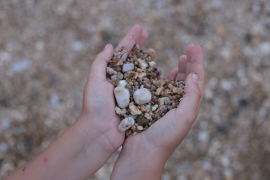 Kumsalda çakıl taşlarıyla el ele tutuşup oynuyoruz.