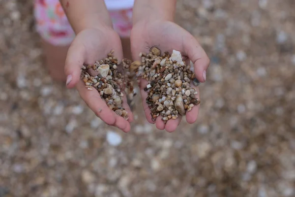 Hands holding and playing with pebbles on the beach