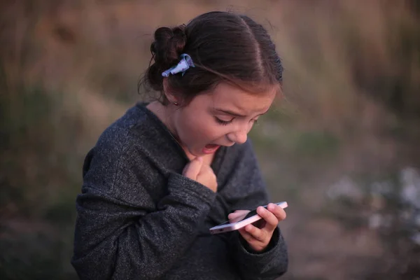 Дівчина Семи Років Різними Емоціями Обличчі Грає Телефоні — стокове фото