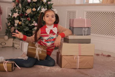 Oyuncu kız Noel 'i kutluyor ve yeni yıl ağacının yanında surat asıyor.