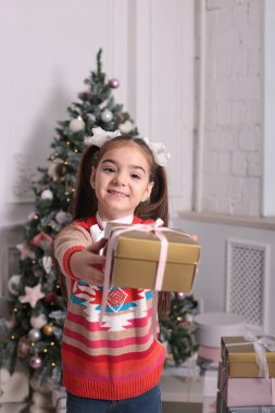 Uzun sarı saçlı, neşeli bir kızın Noel portresi farklı duyguları resmediyor.