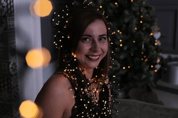 美丽的女孩 一头乌黑的短发 在一棵装饰着的圣诞树旁边有一个花环 — 图库照片