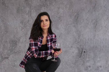 Güzel, ince, kısa siyah saçlı, bordo renkli, damalı tişörtlü, tavan arasında gri bir şarap kadehi olan bir kız.