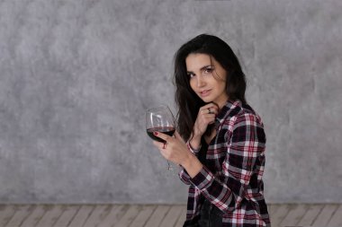 Güzel, ince, kısa siyah saçlı, bordo renkli, damalı tişörtlü, tavan arasında gri bir şarap kadehi olan bir kız.