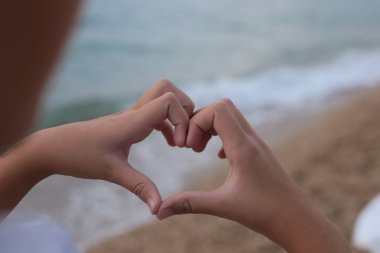 Deniz kıyısındaki kız kumla ve çakıl taşlarıyla oynar doğanın güzelliğini