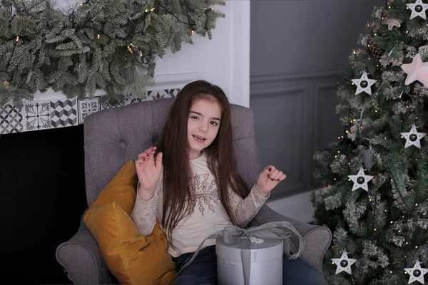 長い黒い髪をした女の子は 装飾されたクリスマスツリーで新年のボケのライトでクッキーで回避しています — ストック写真