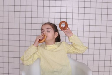 Sekiz yıllık güzel, uzun saçlı, sarı bluzlu, gülümseyen bir kız etrafta aylak aylak dolaşır ve iyi bir ruh hali içinde bir çocuğu buruşturur.