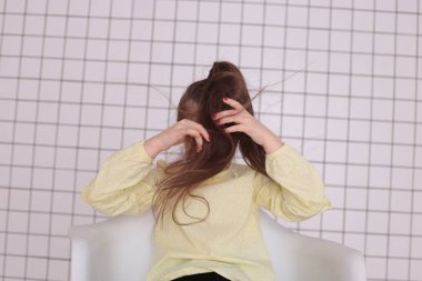 Sekiz yıllık güzel, uzun saçlı, sarı bluzlu, gülümseyen bir kız etrafta aylak aylak dolaşır ve iyi bir ruh hali içinde bir çocuğu buruşturur.