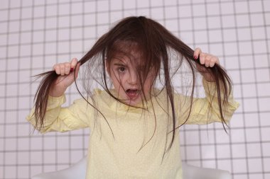 Sekiz yıllık güzel, uzun saçlı, sarı bluzlu, gülümseyen bir kız etrafta aylak aylak dolaşır ve iyi bir ruh hali içinde bir çocuğu buruşturur.