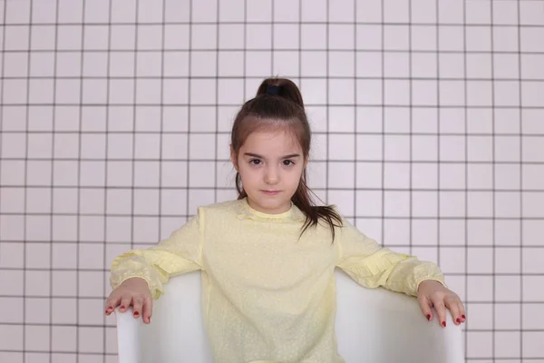 Sekiz yıllık güzel, uzun saçlı, sarı bluzlu, gülümseyen bir kız etrafta aylak aylak dolaşır ve iyi bir ruh hali içinde bir çocuğu buruşturur.