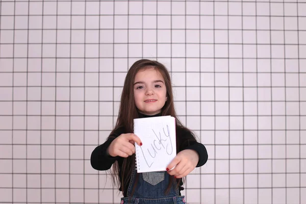 黒のタートルネックのロングヘアで8年の美しい笑顔の女の子と看板のあるデニムのサンドレス ラッキー — ストック写真