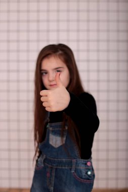 Sekiz yaşında, siyah balıkçı yakalı, uzun saçlı, siyah bir kafesin beyaz arka planında beyaz yakalı, farklı duyguları olan, gülümseyen genç bir kız.