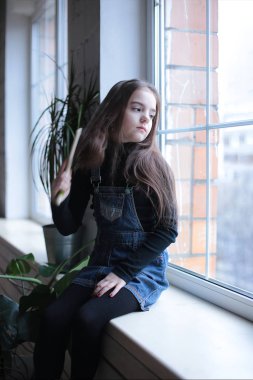 Sekiz yaşında, uzun saçlı, siyah balıkçı yakalı ve üzerinde 