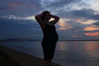 Hamileliğinin dokuzuncu ayında kıvırcık kızıl saçlı genç bir kadın.