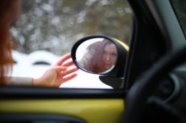 Auto lady on a yellow car in a winter landscape