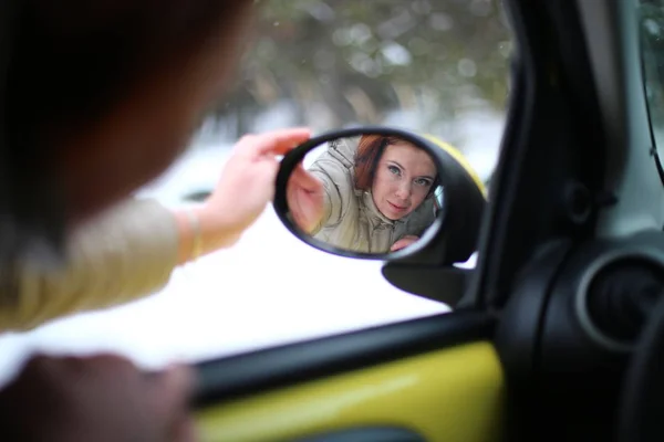 Auto lady on a yellow car in a winter landscape