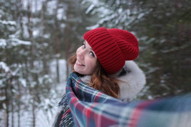 Beautiful young woman with green eyes and red hair in a yellow car in a winter snowy forest