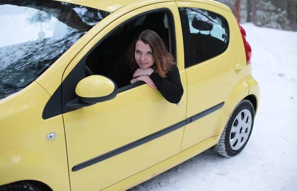 冬の雪の森の中で黄色の車の中で緑の目と豪華な髪を持つ美しい魅力的な女の子 — ストック写真