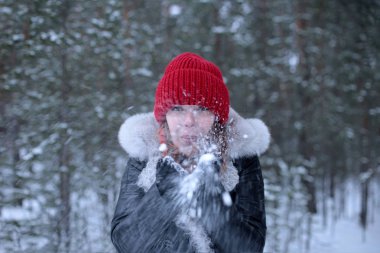 Güzel, çekici, yeşil gözlü, kızıl saçlı bir kız. Kış karlı bir ormanda keyifli bir şekilde yürüyor.