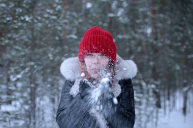 Güzel, çekici, yeşil gözlü, kızıl saçlı bir kız. Kış karlı bir ormanda keyifli bir şekilde yürüyor.