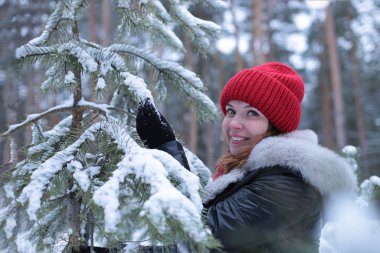 Güzel, çekici, yeşil gözlü, kızıl saçlı, karlı bir ormanda yürüyen bir kız.