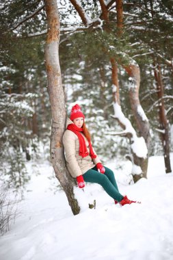 Güzel, çekici, yeşil gözlü, kızıl saçlı, karlı bir ormanda yürüyen bir kız.
