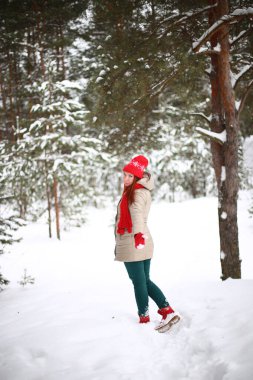 Güzel, çekici, yeşil gözlü, kızıl saçlı, karlı bir ormanda yürüyen bir kız.