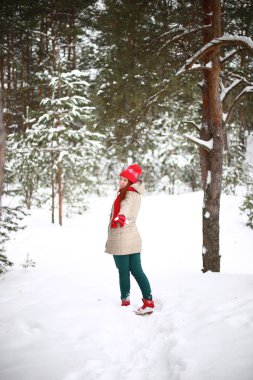 Güzel, çekici, yeşil gözlü, kızıl saçlı, karlı bir ormanda yürüyen bir kız.
