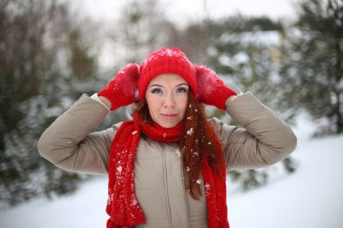 Güzel, çekici, yeşil gözlü, kızıl saçlı, karlı bir ormanda yürüyen bir kız.