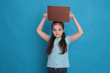 Sekiz yaşında neşeli, sevgi dolu bir kız ve mavi arka planda kayıt için renkli bir sayfa dolusu boş alan.