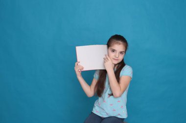 Sekiz yaşında neşeli, sevgi dolu bir kız ve mavi arka planda kayıt için renkli bir sayfa dolusu boş alan.