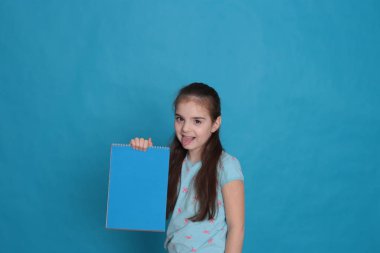 Sekiz yaşında neşeli, sevgi dolu bir kız ve mavi arka planda kayıt için renkli bir sayfa dolusu boş alan.