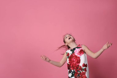 smiling girl of eight years old in a beautiful dress on a pink background joyful spring mood