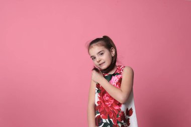 smiling girl of eight years old in a beautiful dress on a pink background joyful spring mood