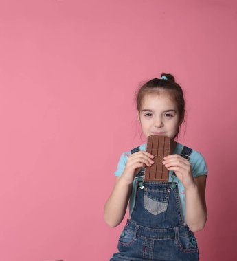 smiling happy girl in a great cheerful mood eating sweet treats chocolate on a bright pink background