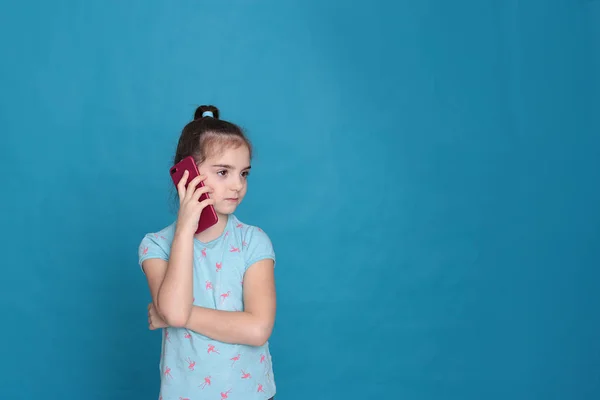Ein Lächelndes Achtjähriges Mädchen Hält Auf Blauem Hintergrund Ein Rosafarbenes — Stockfoto