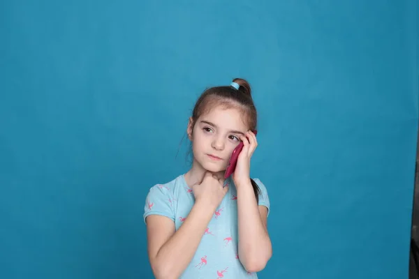 Усміхнена Дівчина Восьми Років Тримає Руках Рожевий Телефон Синьому Фоні — стокове фото