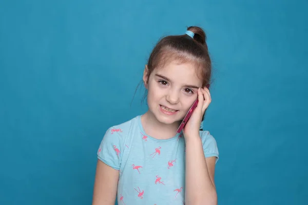Uma Menina Sorridente Oito Anos Segura Telefone Rosa Suas Mãos — Fotografia de Stock