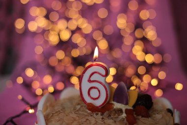 Burning close-up candle in a cake festive bright pink background birthday