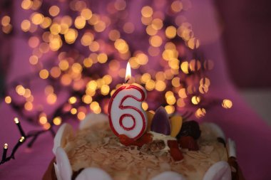 Burning close-up candle in a cake festive bright pink background birthday