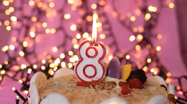 Burning candle in the cake festive bright pink background birthday macro photo