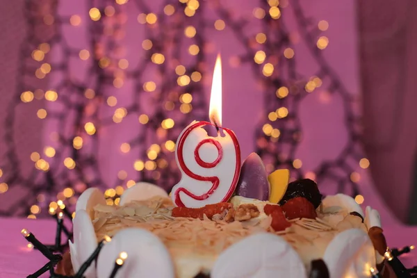 Burning candle in the cake festive bright pink background birthday macro photo